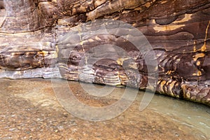 Bizarre of natural coloring of mountains at end of tourist route in canyon of the Mujib River in Wadi al Mujib in Jordan