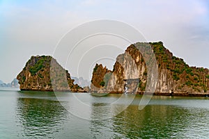 Bizarre shaped rock formations - one looking like human face in profile, one with holes - in South China Sea, Ha Long Bay, Vietnam