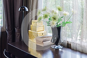 Bkack vase of flower on wooden table with black lamp