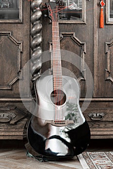 Black acoustic guitar with red strings. Guitar in vintage classic wooden interior