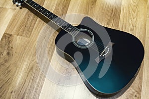 Black acoustic guitar on the wooden floor