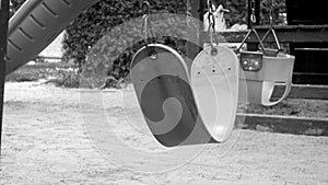 Black adn white image of empty swings on children playground at park