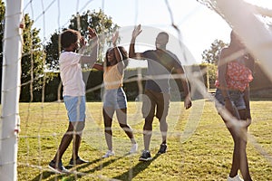 Black adult friends high five during a fun game of football