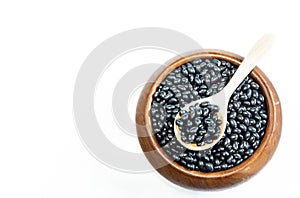 Black adzuki bean on wooden spoon in wooden bowl on background.