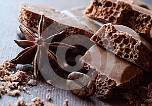 Black aerated chocolate in bars with anise and coffee beans,food background,horizontal composition