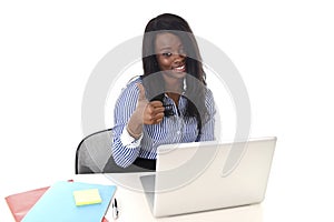 Black african american ethnicity woman working at computer laptop at office desk smiling happy