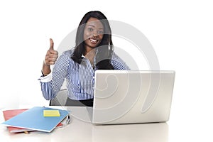 Black african american ethnicity woman working at computer laptop at office desk smiling happy