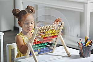 A Black African-American girl is ready for a math and arithmetic lesson with an abacus.