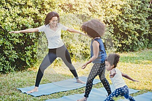 Black African American mom with child playing yoga family activity together at backyard during self quarantine at home