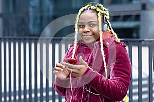 Black african american pensive girl with yellow hair, happy young woman listening to music on headphones, earphones