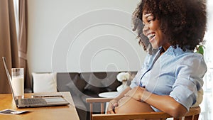 Black African American Pregnant woman showing her belly on laptop