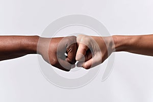 Black African American race female hand touching knuckles with white Caucasian woman in multiracial diversity