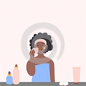 A black African-American woman is washing her face with cosmetics in the bathroom