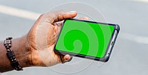 black african hand holding and using green blank screen mobile phone horizontally
