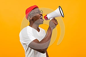 Black african man speaks in megaphone on isolated yellow background