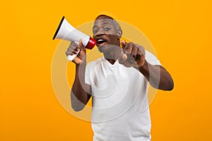 Black african man speaks in megaphone on isolated yellow background