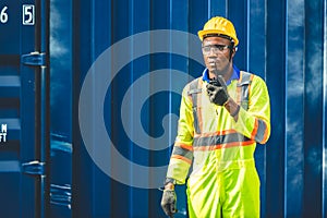 Black African worker working in logistic shipping radio control order command loading containers at shipping port. staff cargo for