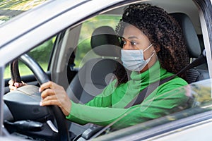 Black afro woman driving and wearing face mask