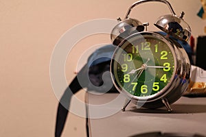 Black alarm clock on blue background, soft focus, selective focus