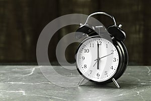 The black alarm clock hands point to six o`clock