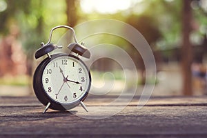 Black Alarm Clock vintage on wooden table and abstract background