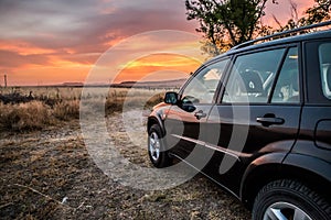 Black all terrain car stopped in nature with the sunset in the s