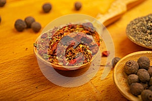 Black allspice, coarse salt and various ground spices in wooden spoons on a wooden Board. Close up