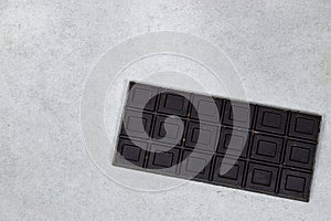 black almond chocolate bar isolated on grunge gray background from top view.