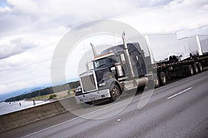 Black american big rig semi truck on interstate highway