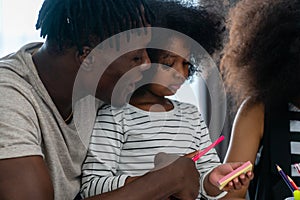 A black american father his daughters are doing their homework in the living room