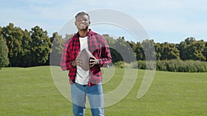 Black american football player throwing ball on green field during game