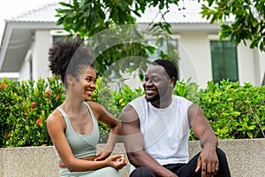 A black American man and woman couples resting after exercising in the garden chatting and smiling cheerfully at each other