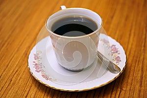 Black Americano coffee in a porcelain cup on a brown wooden walnut table photo