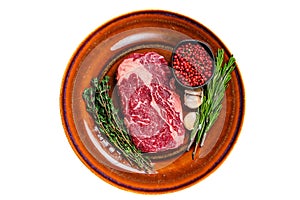 Black angus rib eye raw beef steak on a rustic plate. Isolated on white background.