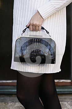 Black art deco crocodile purse and white sweater fashion detail