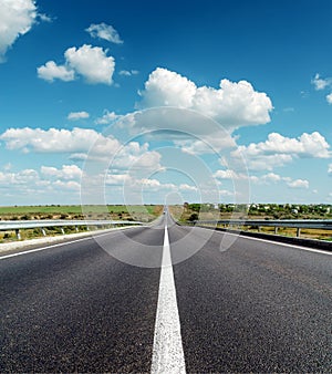 Black asphalt road under deep blue cloudy sky