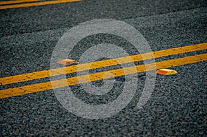 Black asphalt road with yellow lines and orange reflectors