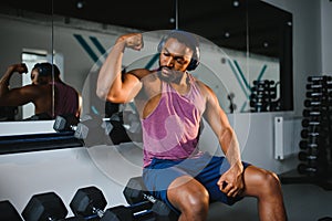 Black athlete flexing muscles, demonstrating strong biceps in gym
