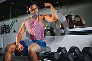 Black athlete flexing muscles, demonstrating strong biceps in gym