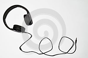 Black audio headphones and cord on white background