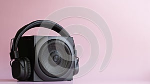 Black audio speaker and headphones with ambryushores on a pink background. Pop music concept. Free space for text, inscription,