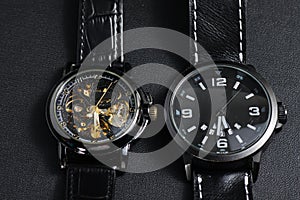 A black automatic self winding wristwatch with transparent sekeleton dial design and a black battery operated watch