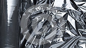 Black background. Black shiny film bag pattern. Wrap transparent dark cellophane texture. Creative crumpled background.