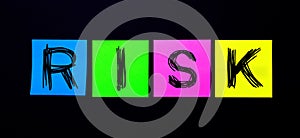 On a black background, bright multicolored stickers with the word RISK. Illustration