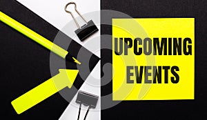 On a black background, a bright yellow pencil and an arrow and a yellow sheet of paper with the text UPCOMING EVENTS