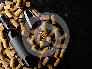 On a black background a lot of wine corks, a bottle of red wine and a wine glass. Romantic date, holiday, banquet, restaurant,