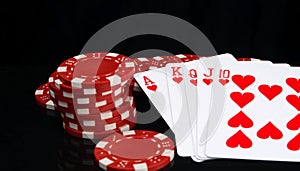 On a black background with reflection, red chips and a winning hand, in poker, close-up