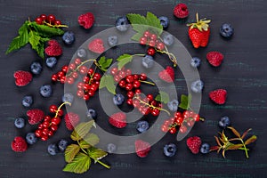 Black background with a set of red and blue berries with green leaves