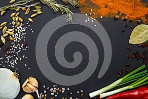 On a black background spices and vegetables. View from above.