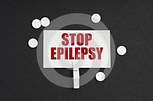 On a black background, there are pills and a business card with the inscription - STOP EPILEPSY